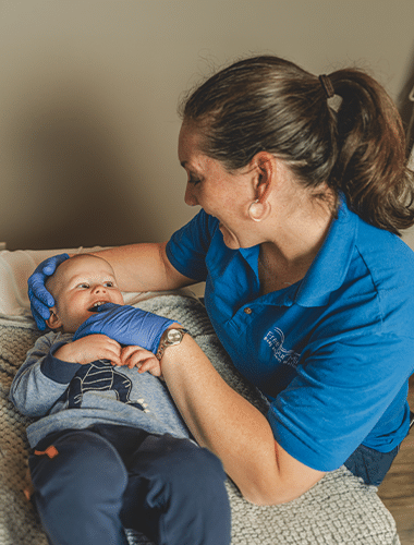 Pediatric healthcare provider gently examines an infant on an examination table, ensuring a comfortable and caring environment.